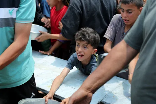 Lačen otrok čaka na razdeljevanje hrane, kamp Nuseirat, Gaza.
