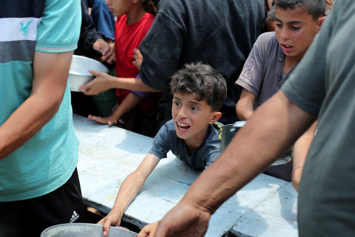 Lačen otrok čaka na razdeljevanje hrane, kamp Nuseirat, Gaza.